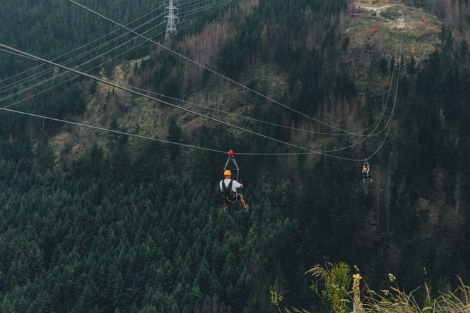 Two people zip lining over the forest at Christchurch Adventure Park