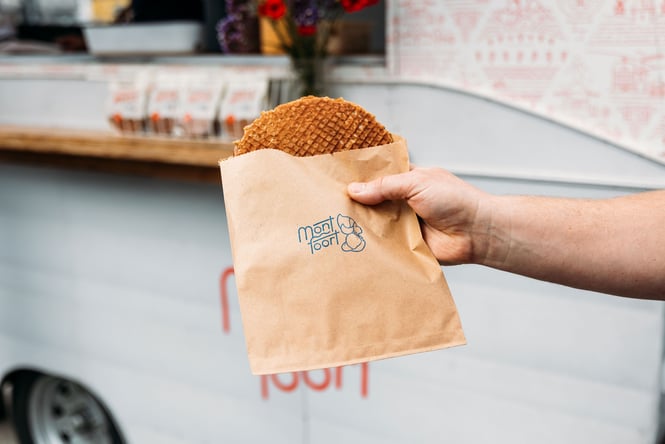 Someone holding a stroopwafel outside a food truck