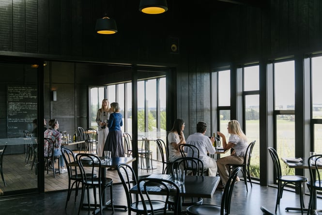 Customers dining inside a black dining room inside Black Estate.