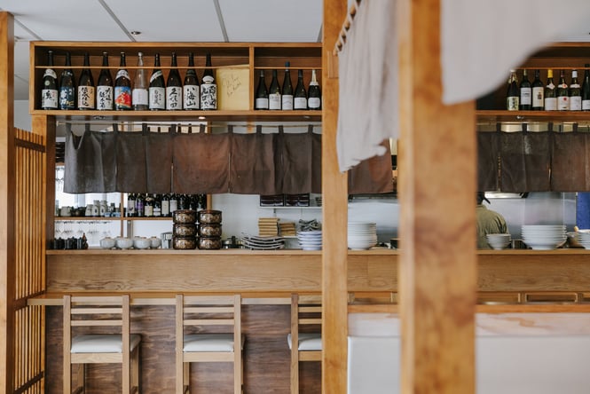 Looking over the counter into the kitchen where the chef is.