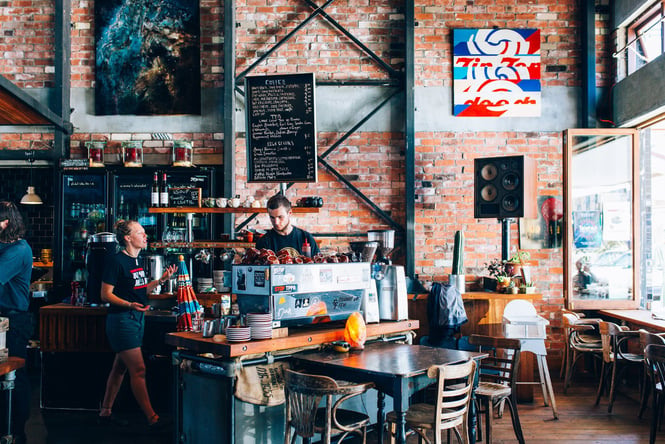 People sitting inside the Lyttelton cafe with a red brick wall behind them.