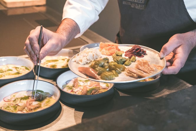 A chef using chopsticks to plate up the final details of a meal.