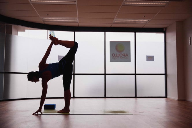 A woman doing a stretch in the dark at Apollo Power Yoga.