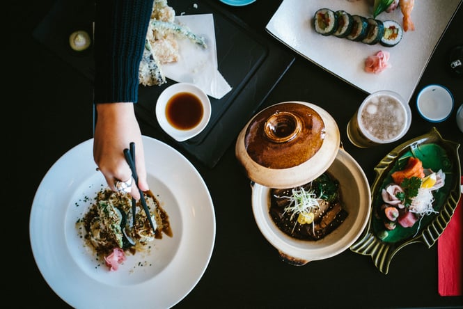 A flatlay of sushi and other Japanese food on black plates.