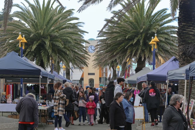 People walking through market stalls on a cloudy day.