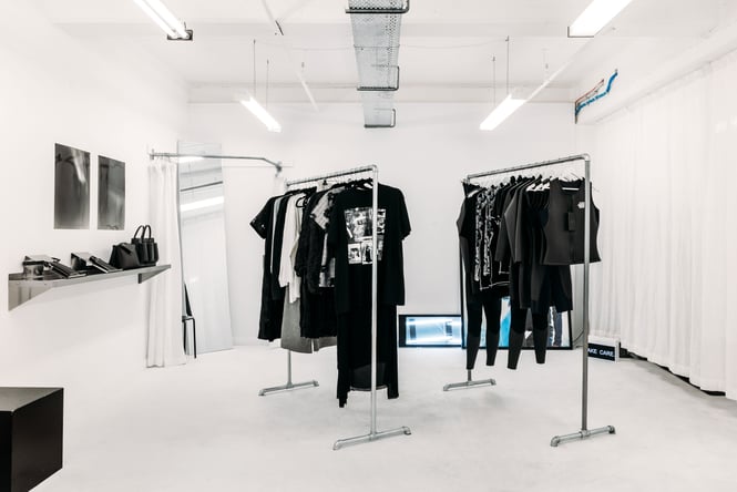 Black clothing on display inside a crisp white interior of a retail store.