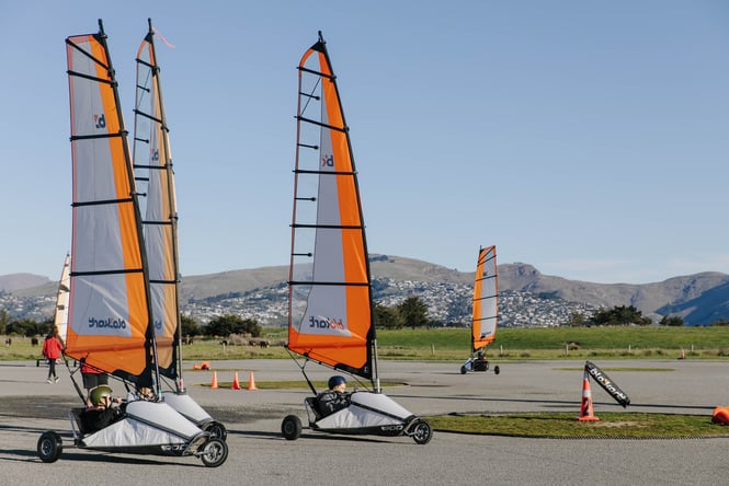 A group of people going around the track in orange blokarts