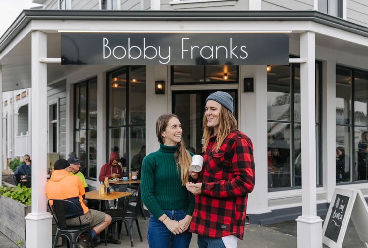 Kiera and Marc Shaw of Bobby Franks smiling at each other outside their Nelson cafe.