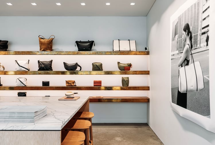 Leather bags on display on wooden floating shelves.