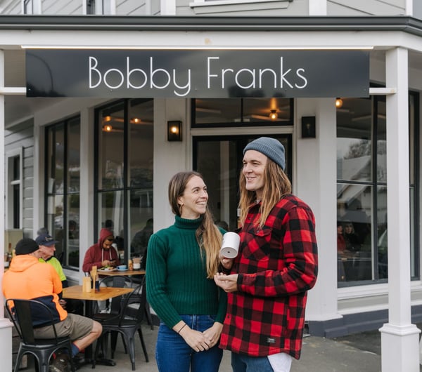 Kiera and Marc Shaw of Bobby Franks smiling at each other outside their Nelson cafe.