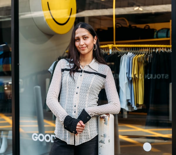 A woman wearing black and white standing in front of a clothing store.