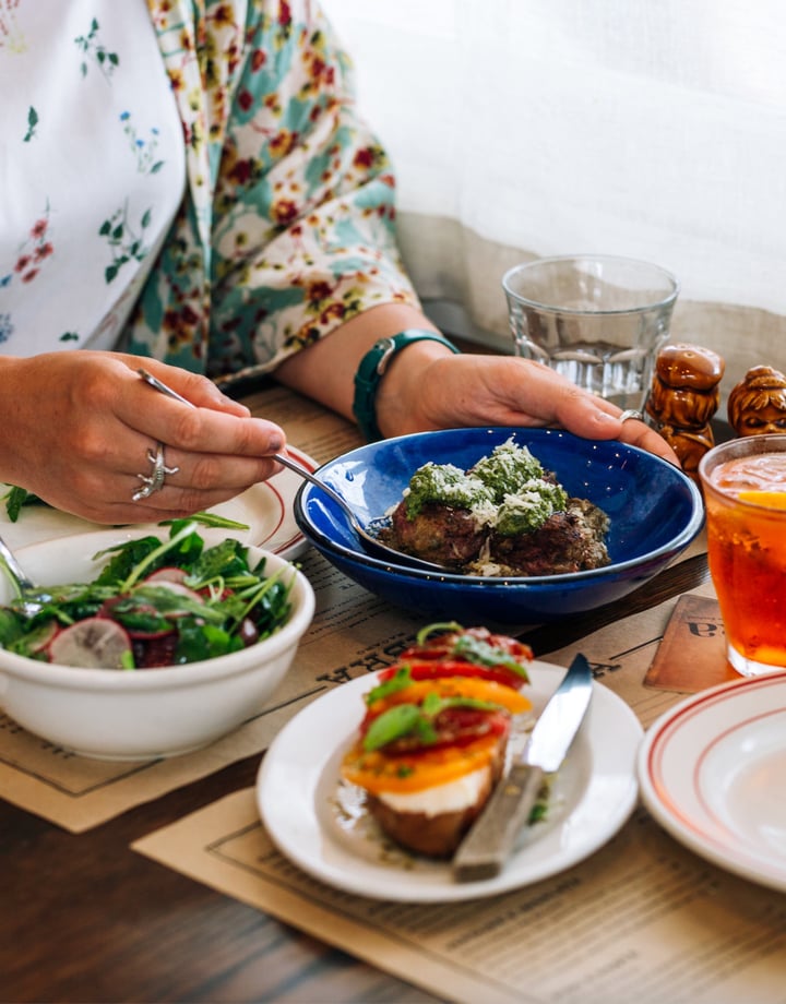 A woman sitting at a table with plates of food at Ombra Wellington.