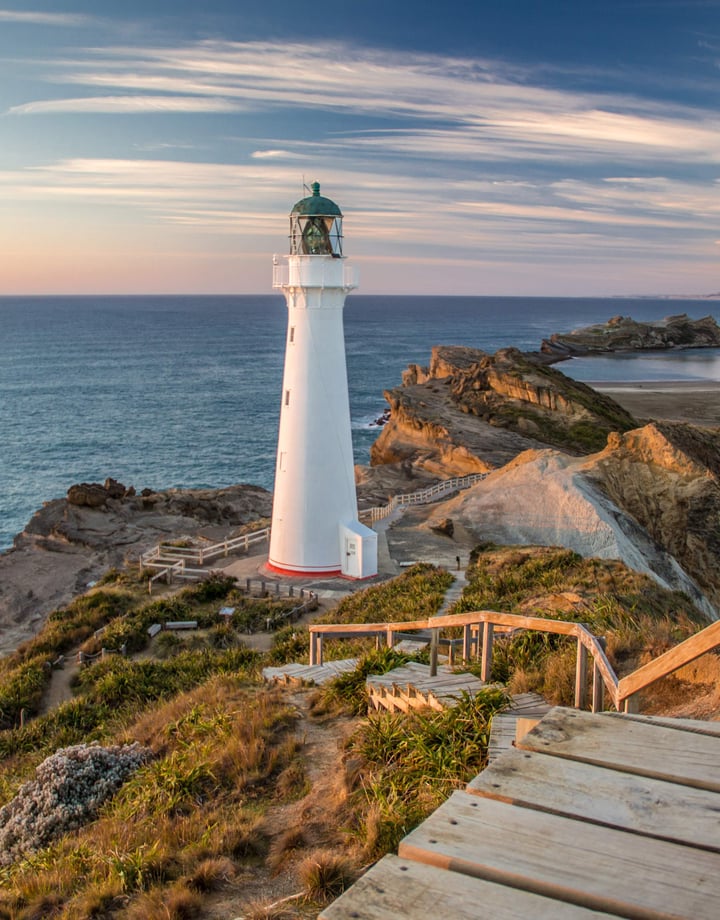 A view of a white light house at dusk at Castlepoint in New Zealand.