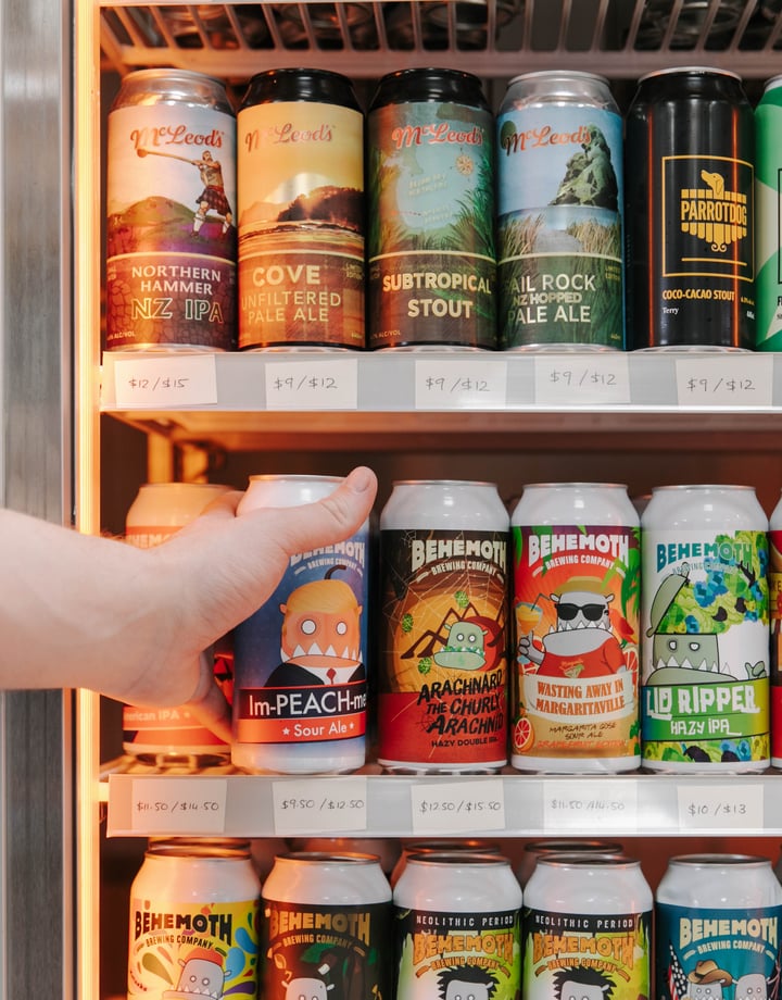 Hand reaching into fridge to grab a can of craft beer.