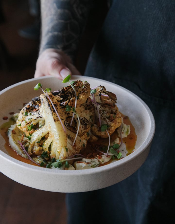 Waiter at Cucina holding a cauliflower dish.