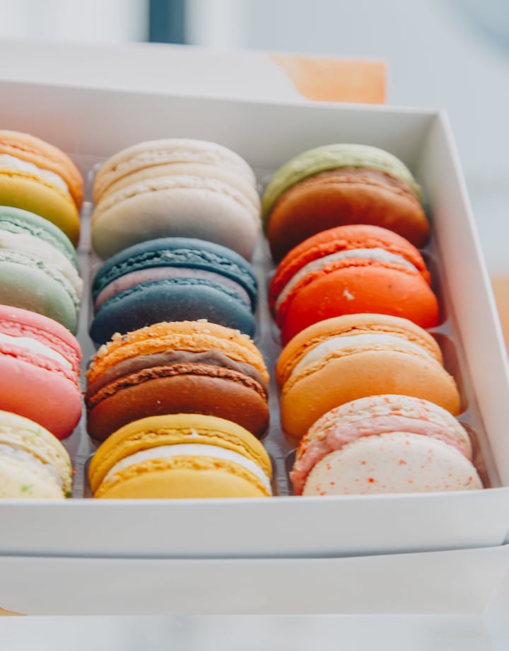 Brightly coloured macaroons in a white box.