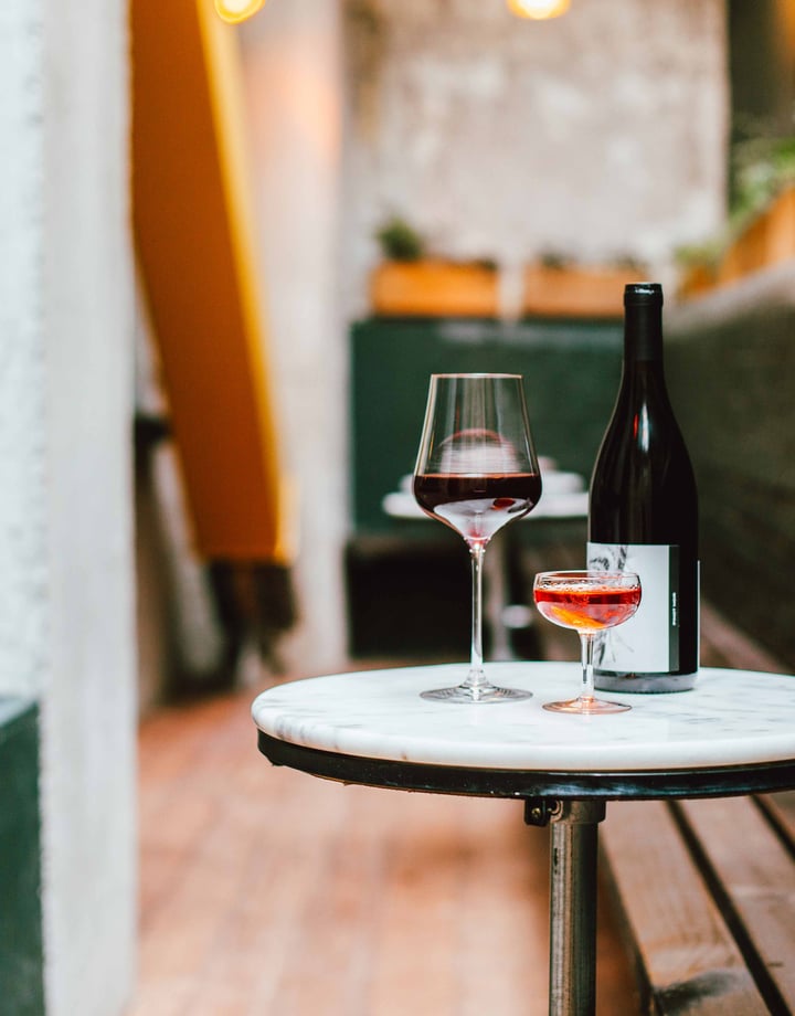 Glasses and a bottle of wine sitting on a table in the outdoor seating area of Puffin Wine Bar in Wellington.