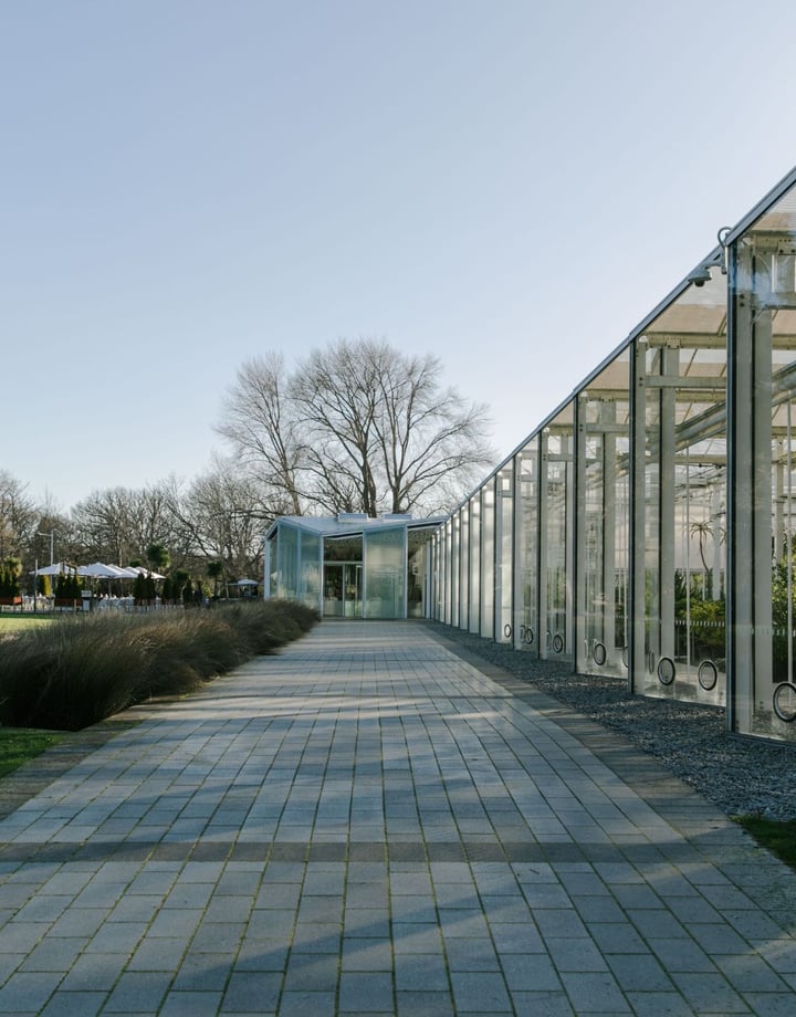 A big glass house filled with rows of plants.