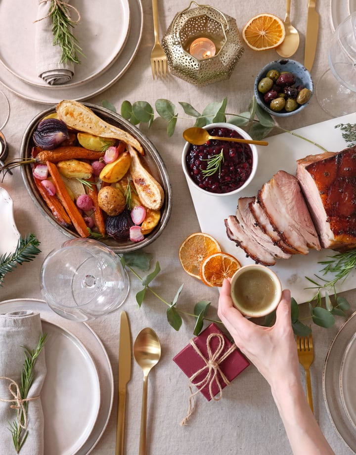 A hand holding a glass of champagne over a Christmas table setting.