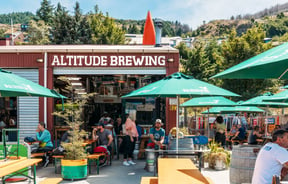 The colourful exterior of Altitude Brewing surrounded by large green umbrellas.