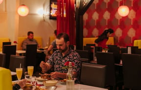 Man sitting at a table serving himself curry.