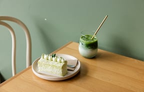 A close up of a dessert and green juice on a table.