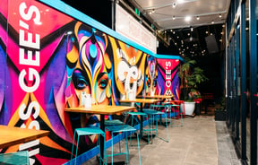 Tall bar seats alongside a graffiti wall inside Miss Gee's Tauranga.