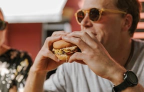 A close up of a man holding a burger.