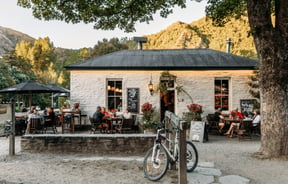 Customers dining outside a quaint stone building in Arrowtown.