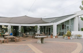 View of the outdoor dining area and brick courtyard under the shade sail at The Mediterranean Food Company, Christchurch.