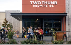 Exterior of Two Thumb Harbourside with people drinking and eating at tables
