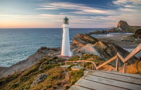 A view of a white light house at dusk at Castlepoint in New Zealand.
