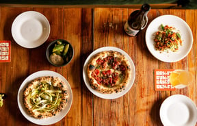 A flatlay of plates of pizza and drinks on a table.