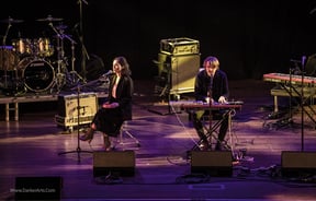 A man and woman playing musical instruments on a stage.