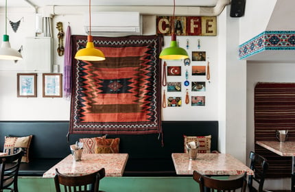 Chairs and tables in kebab shop with Turkish decor and tapestry on walls