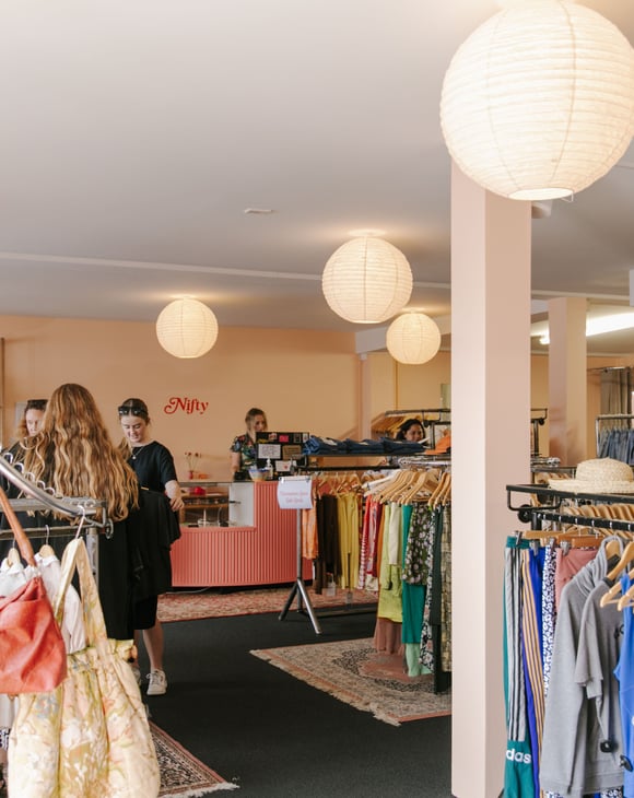 The busy and bright interior of a second hand clothing store.