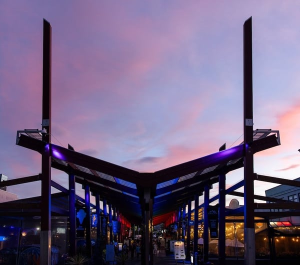 The V-shaped roof structure of Eat Streat against a pink and blue dusky sky.