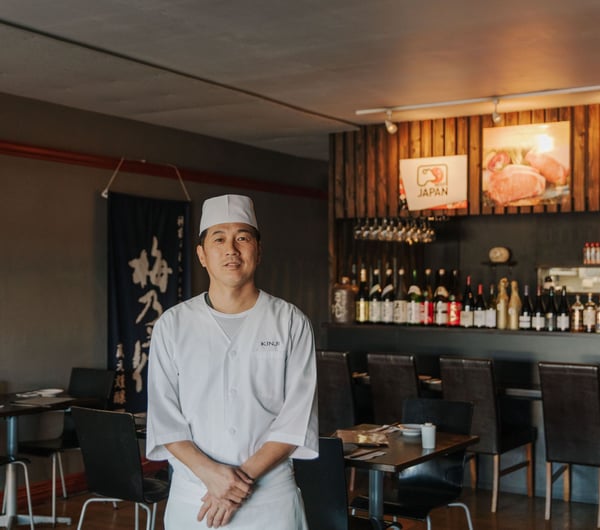 The Chef of Kinji Japanese restaurant standing in the middle of the restaurant smiling.