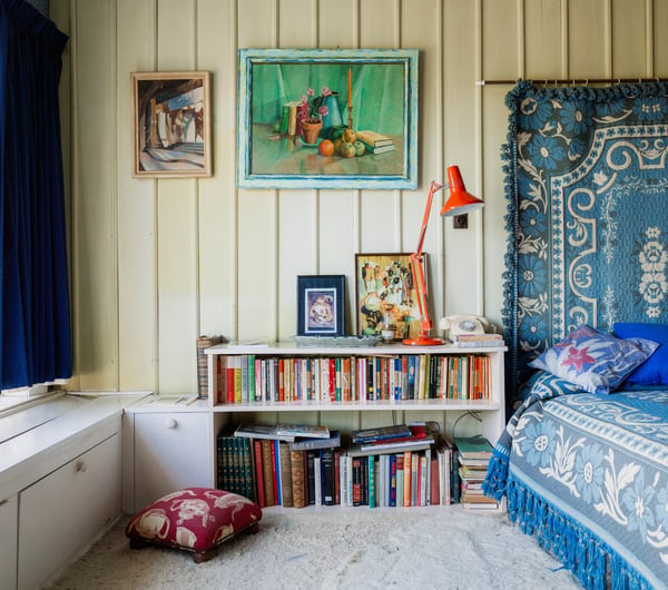 A colourful bookshelf by an old bed in the Ngaio Marsh House.