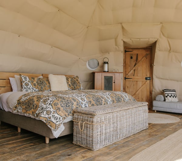 A bedroom set inside a Glamping pod with a wooden panelled floor.