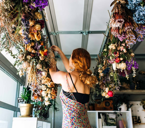 A woman working on bouquets hanging from the ceiling.