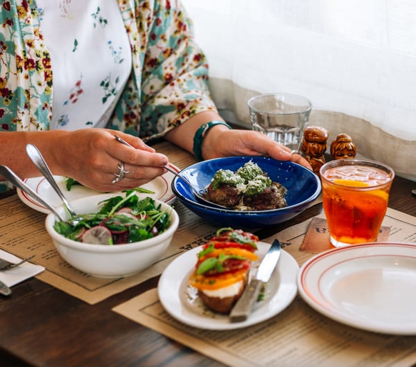 A woman sitting at a table with plates of food at Ombra Wellington.