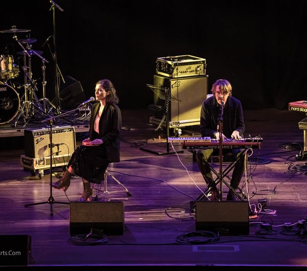 A man and woman playing musical instruments on a stage.
