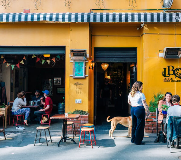 People dining outside a bar that has a yellow painted exterior.