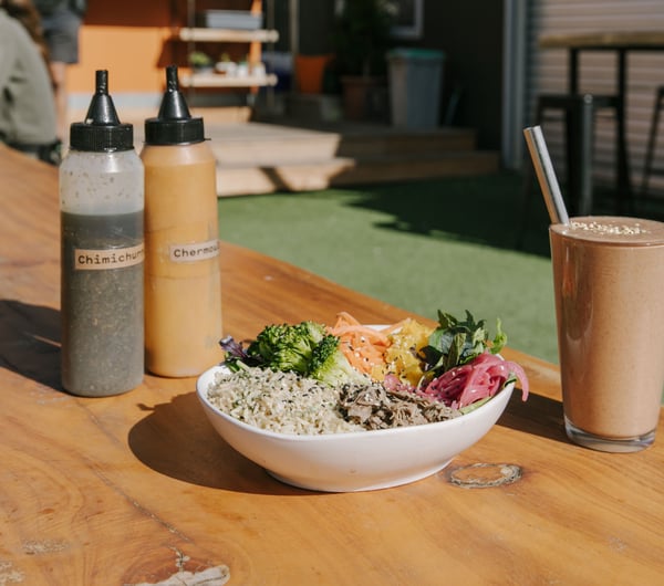 A healthy salad bowl and smoothie on a table outside at Dripping Bowl Wanaka.