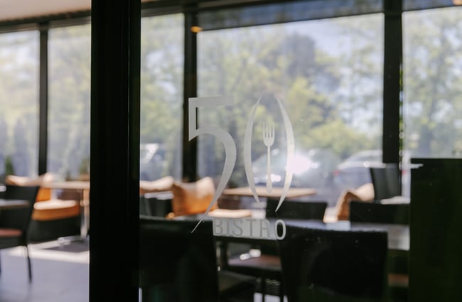 The glass door into 50 Bistro with a vinyl sign on it.