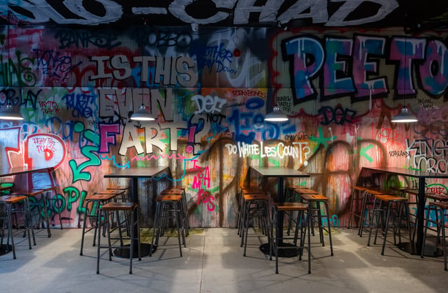 High tables and chairs next to graffitied walls.