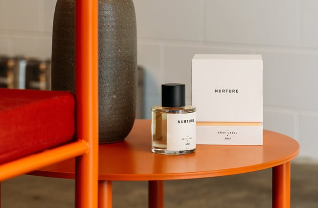 An orange chair and table with a bottle of perfume displayed.