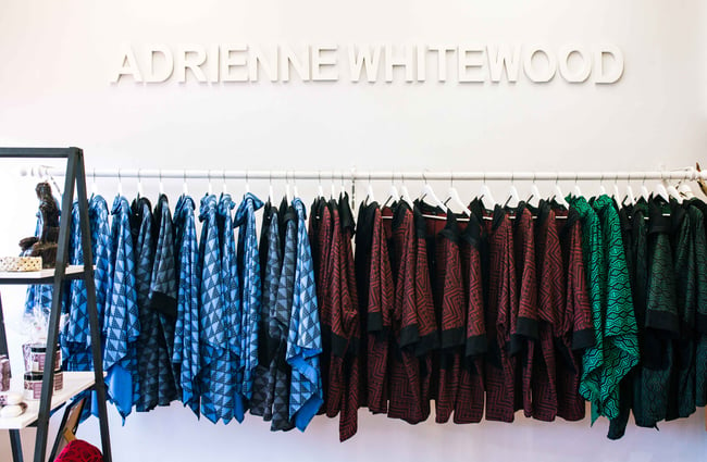 Adrienne Whitewood clothes on display on a rack below the same name displayed on the white wall.