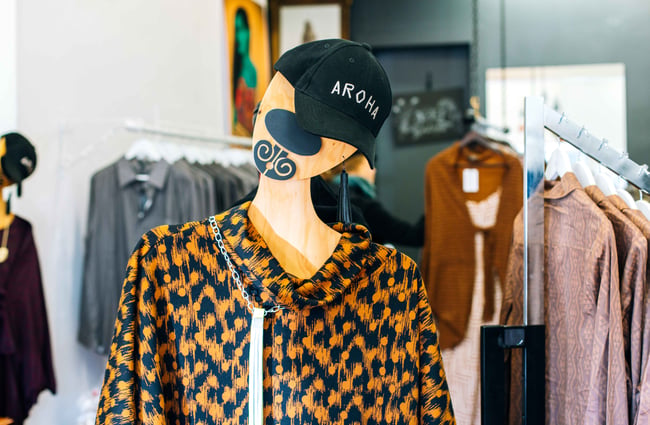 A dressed mannequin wearing an embroidered 'Aroha' black cap.